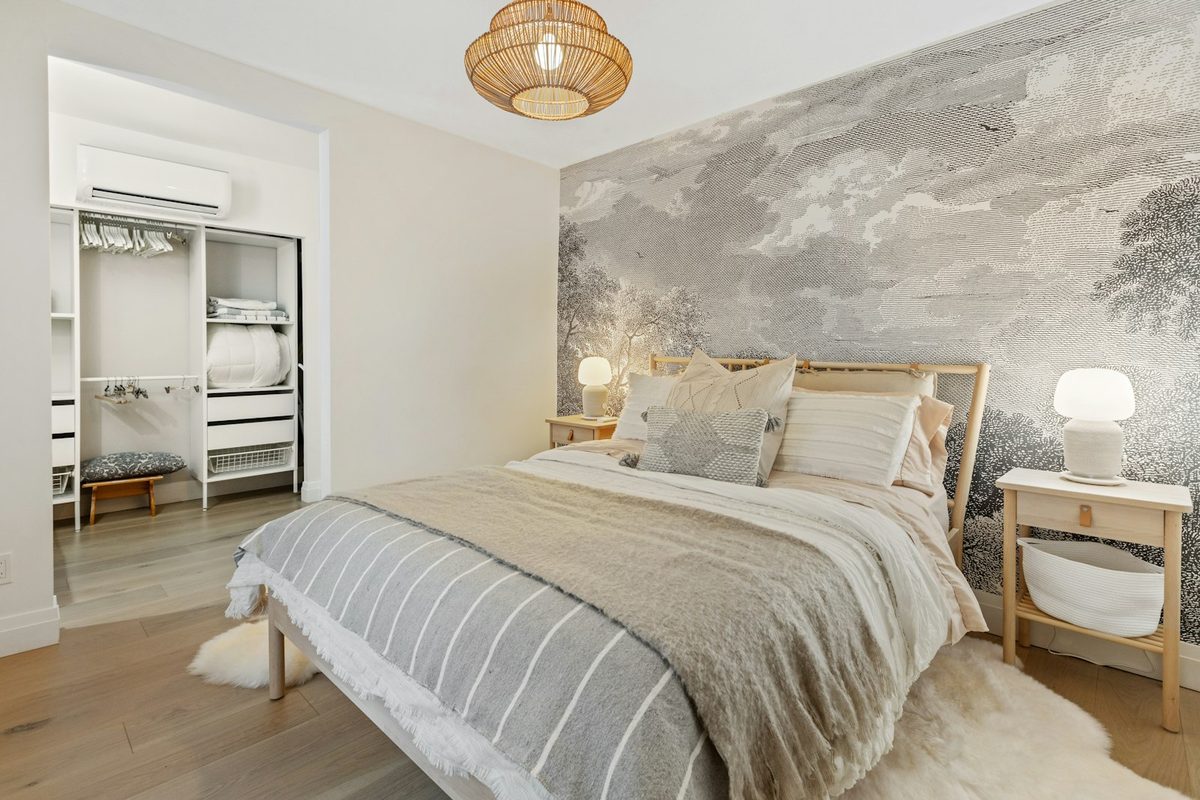Bett mit mehreren Lagen heller Bettwäsche und Kissen.